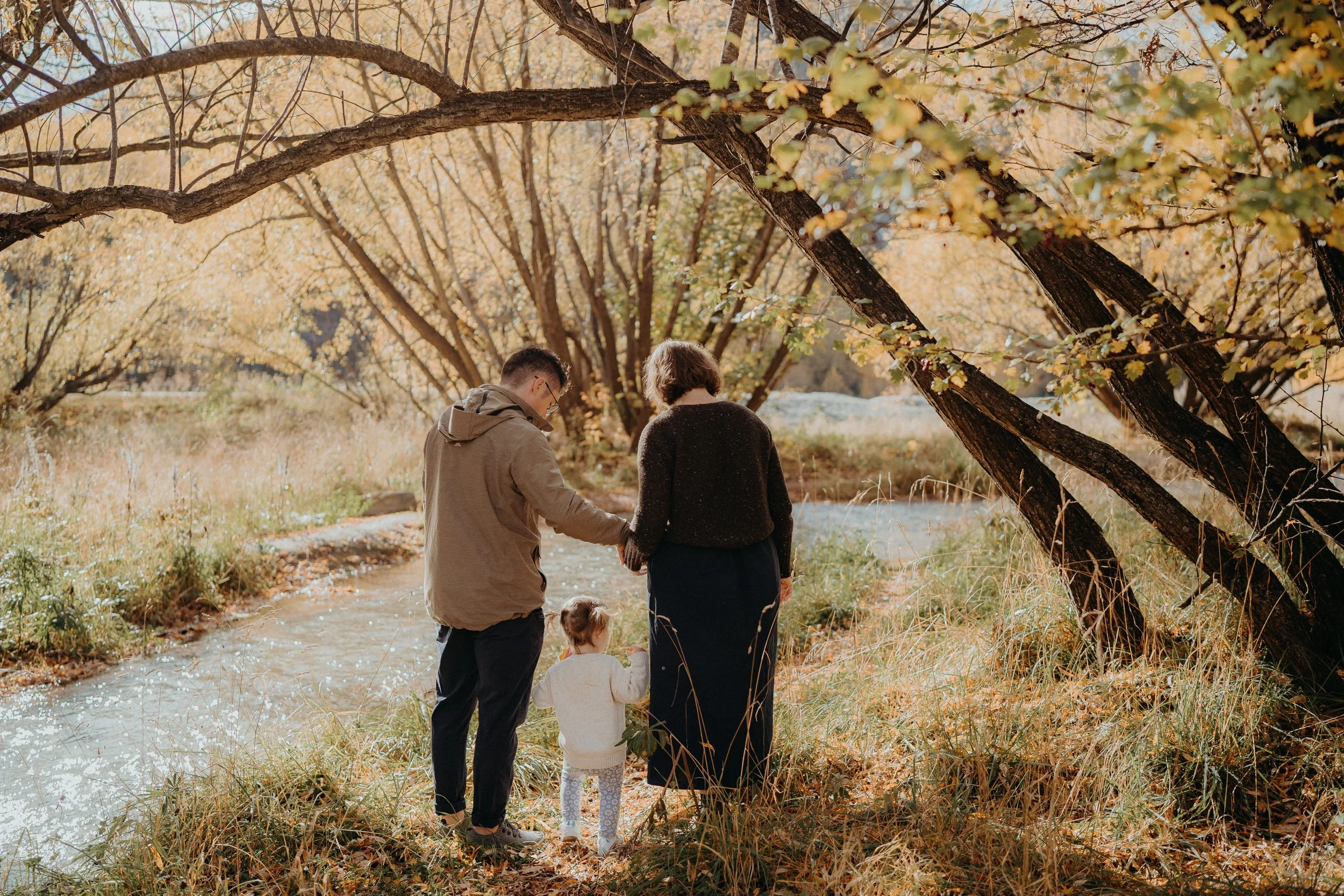 Family of 3 standing next to Arrowtown river in Autumn