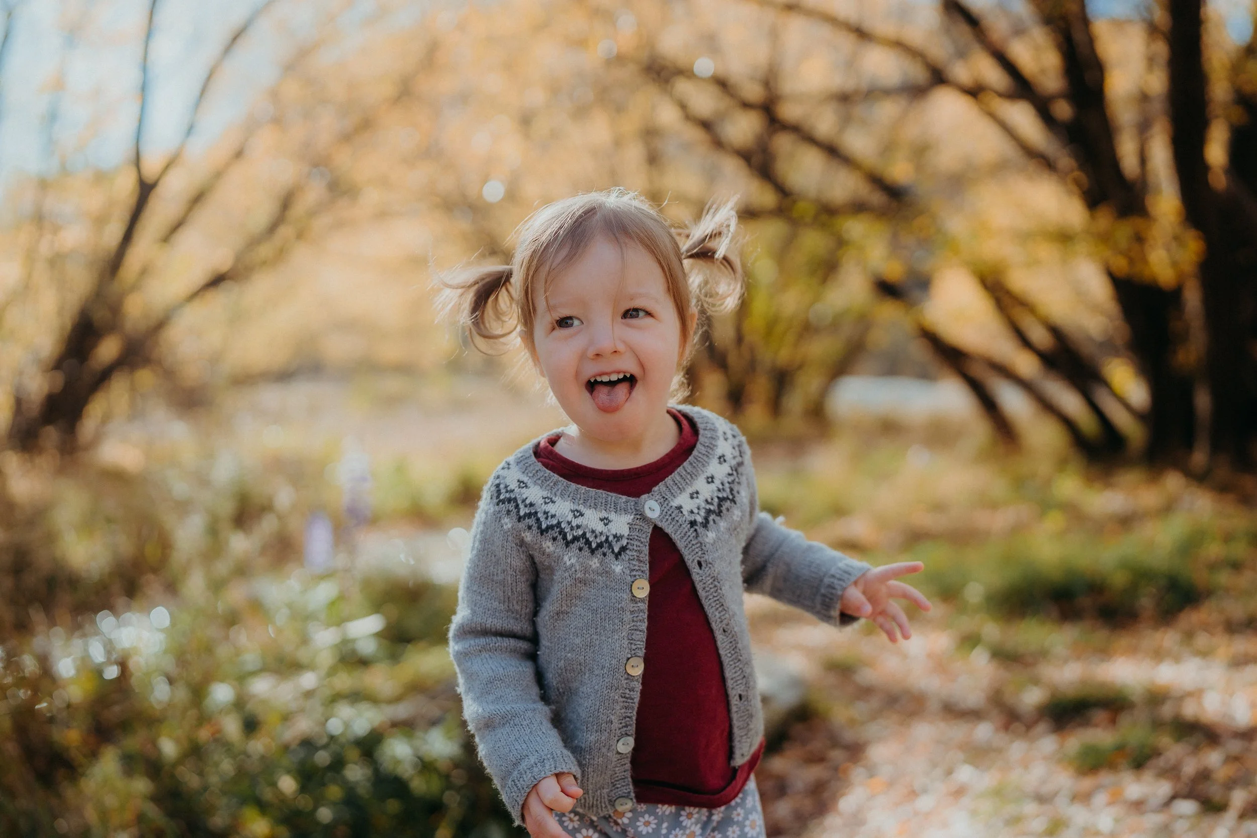 Small child smiling in front of yellow arrowtown trees