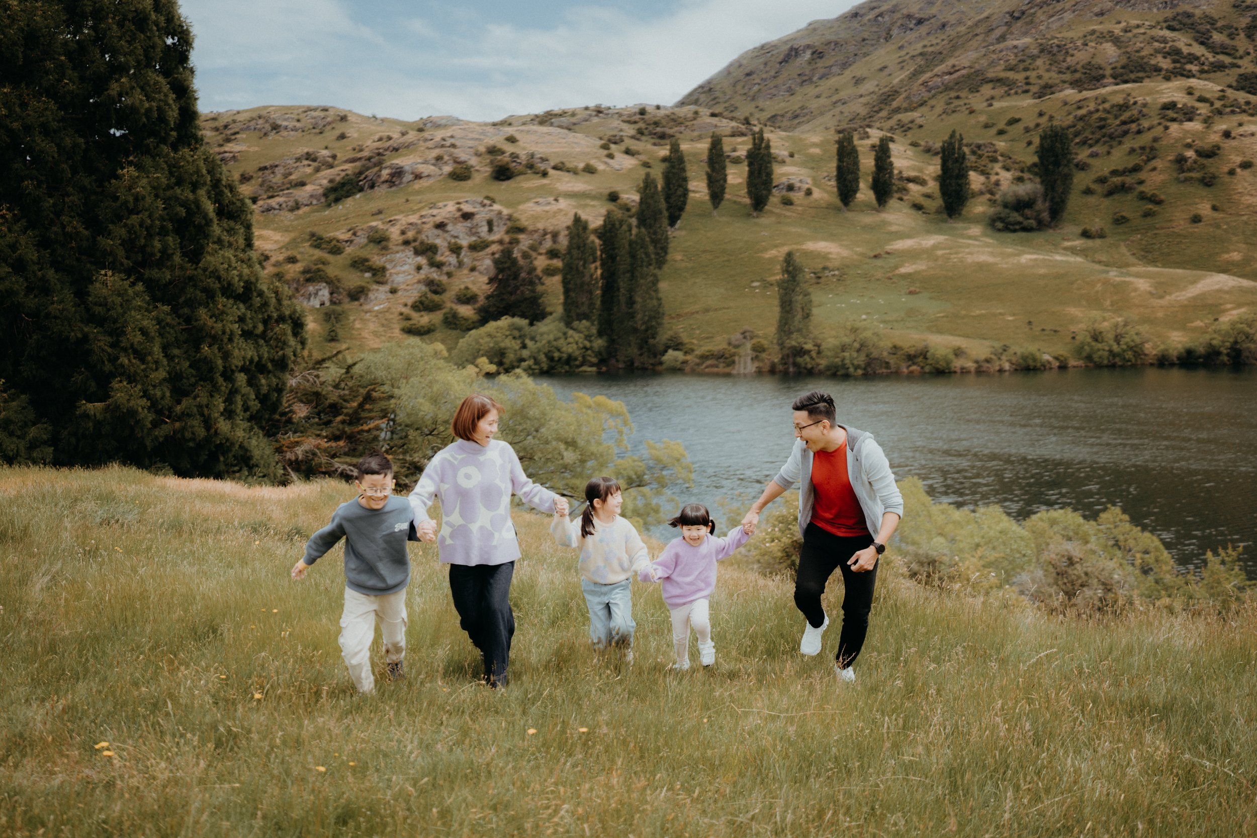 Family of 5 running through grassy green field