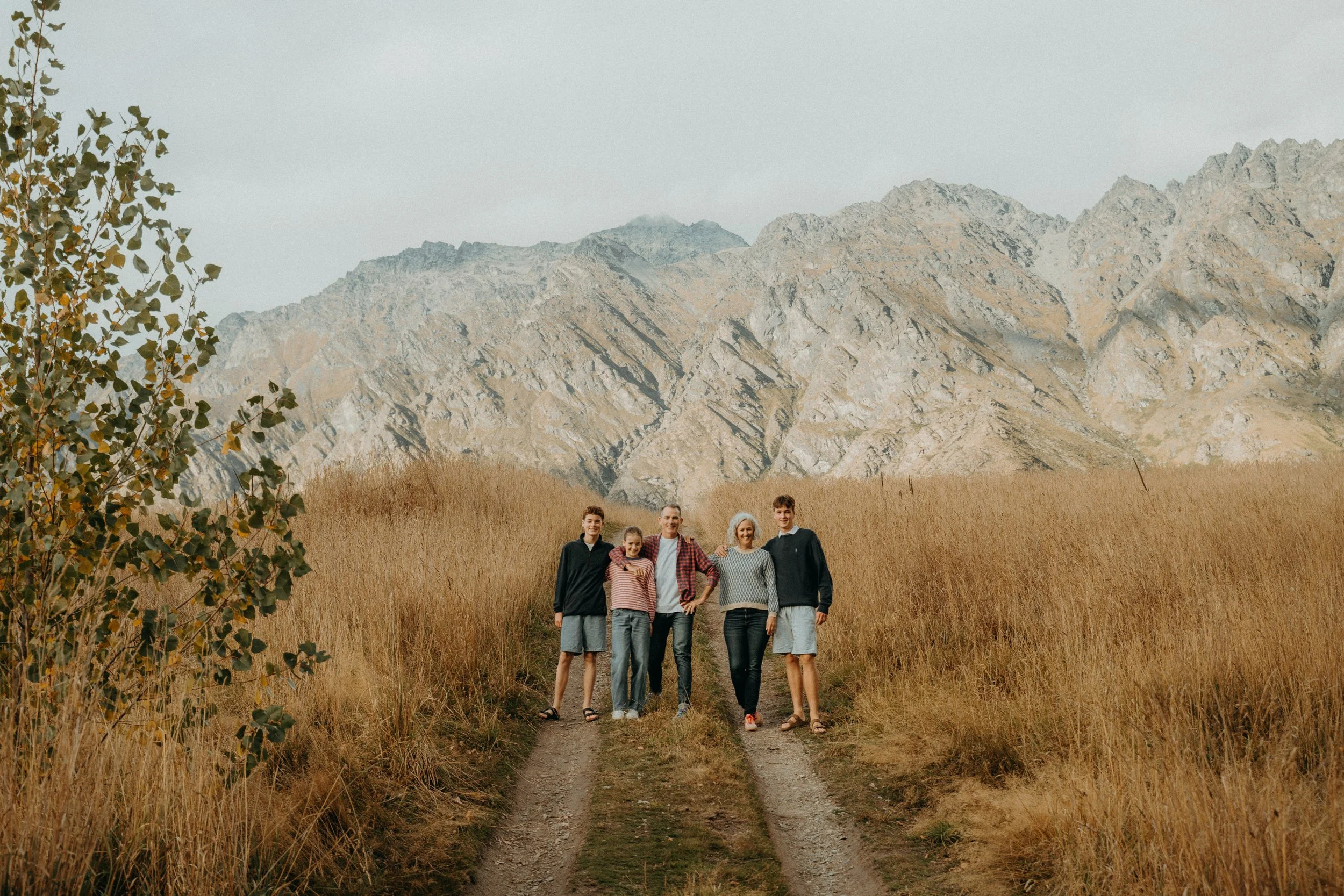 Family standing on grassy golden hill in front of the remarkable mountains