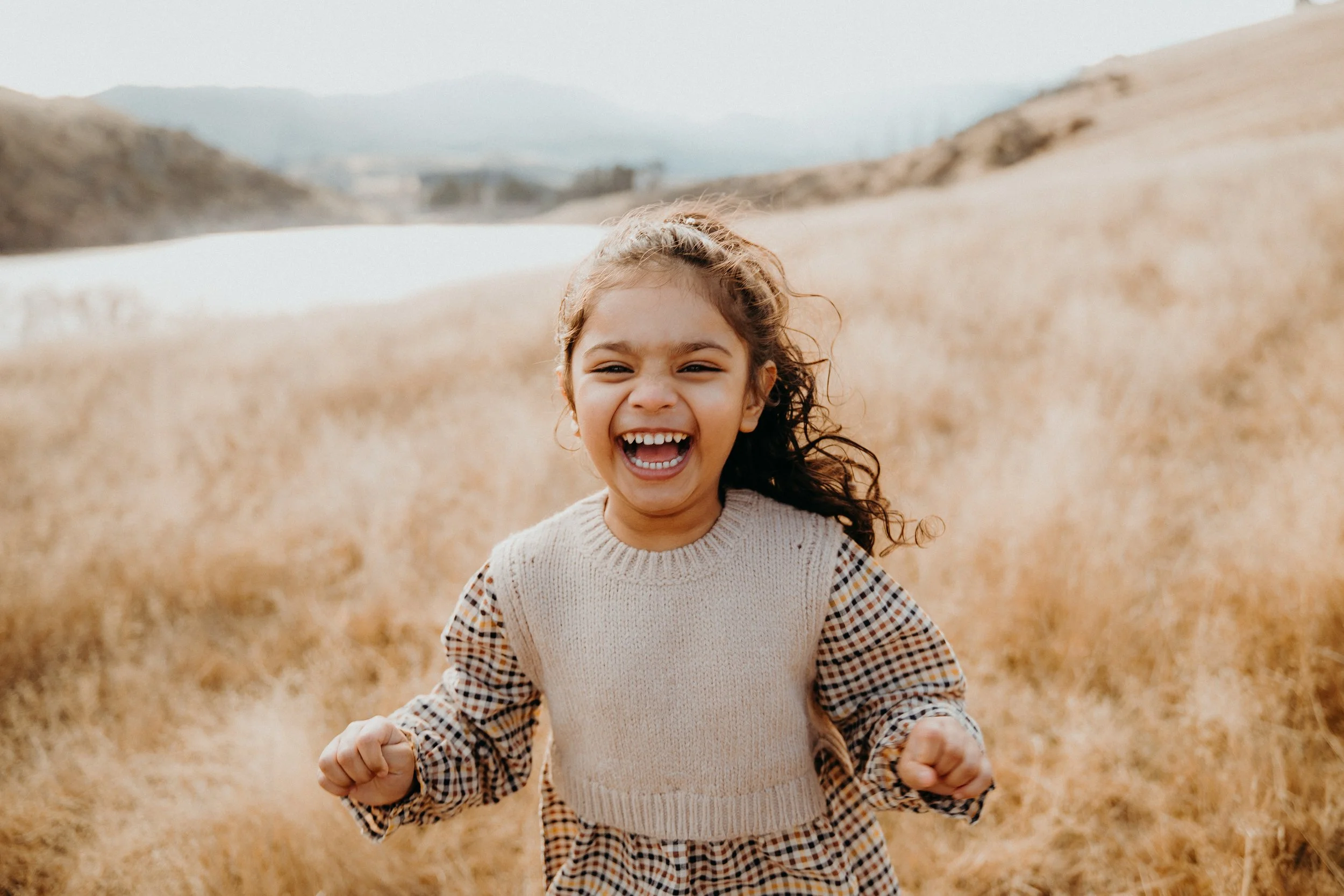 Small child laughing on grassy hill
