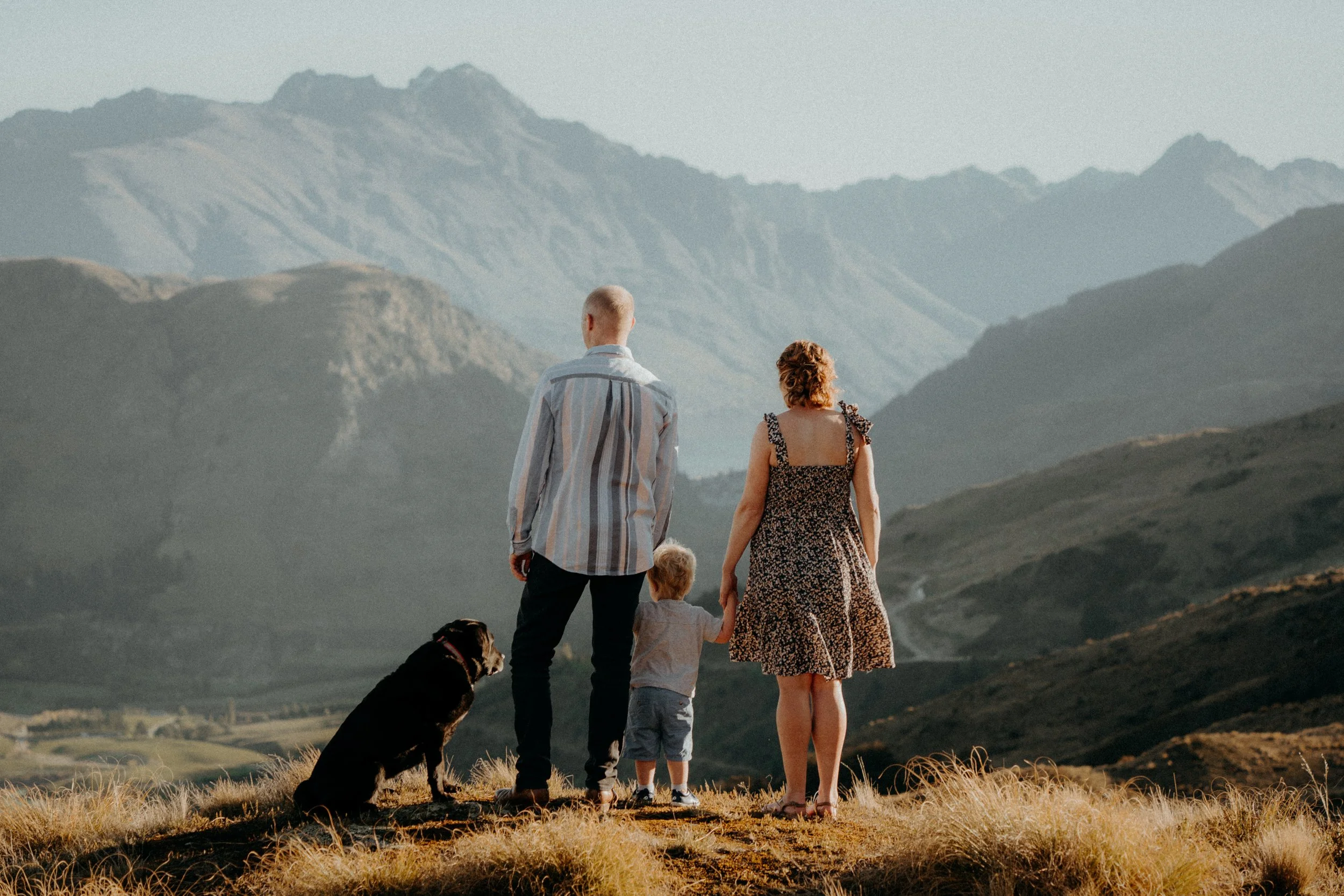 Mother and father looking out at mountains with their son and dog