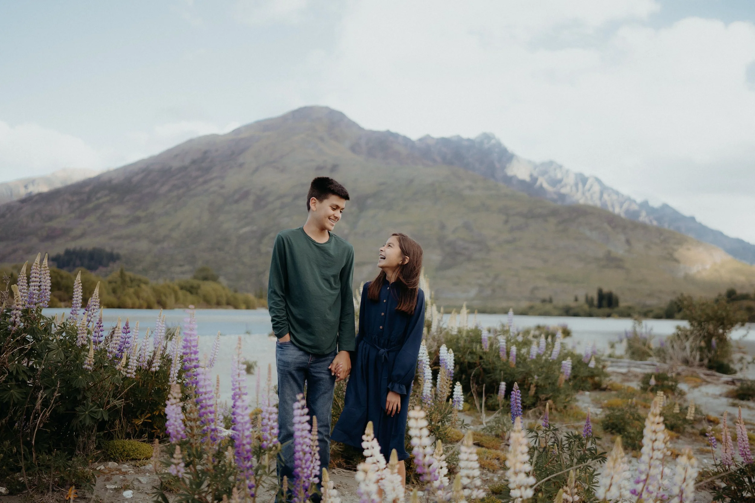 Siblings smiling at eachother in lupin field at the old shotover bridge