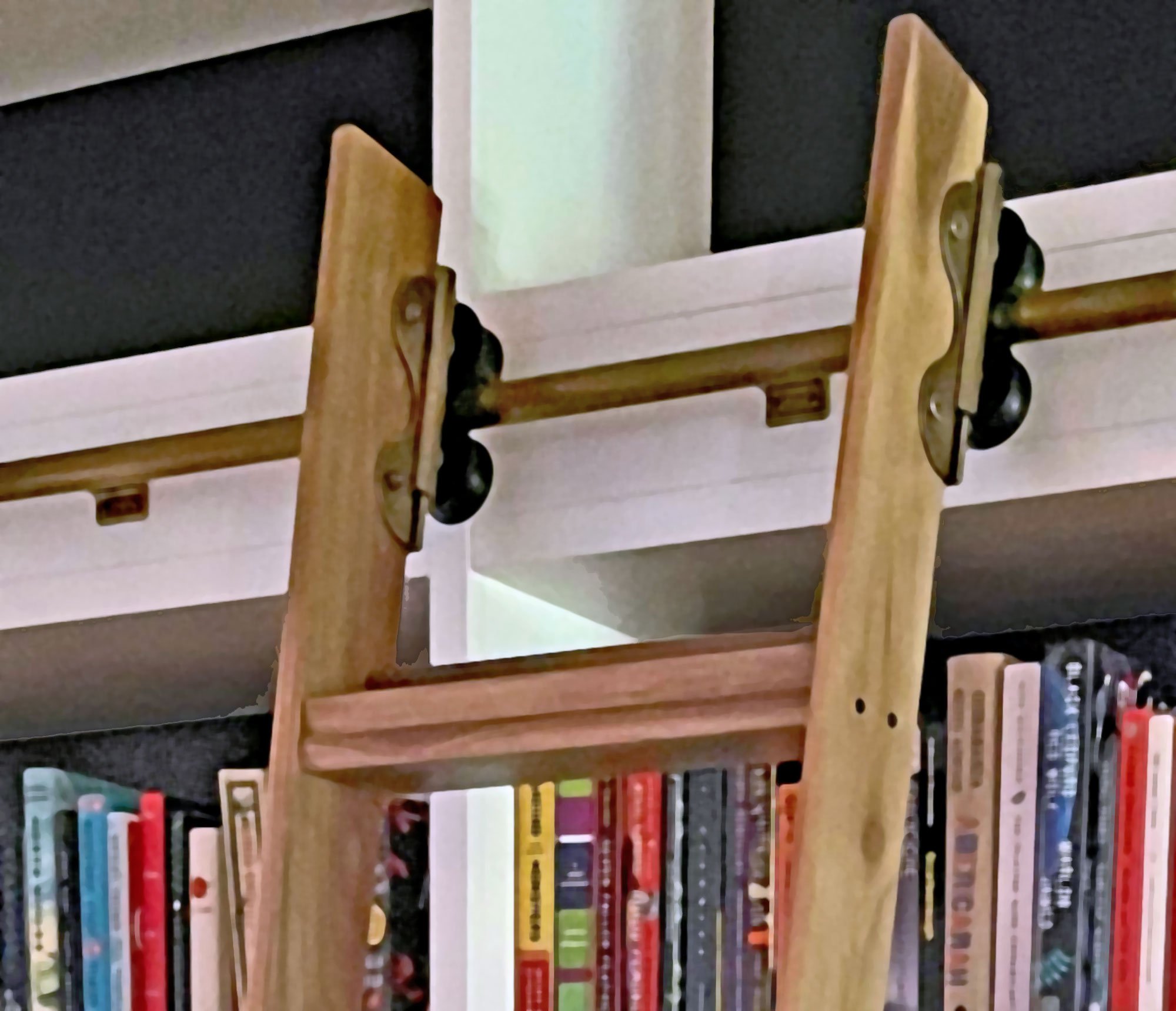 Close-up of a library ladder showing BOOKIE, a small shelf at the top of the ladder . A more contemporary version of a traditional top rung which also increases safety