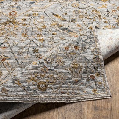 Close-up of a floral-patterned rug with earth tones on a wooden floor.
