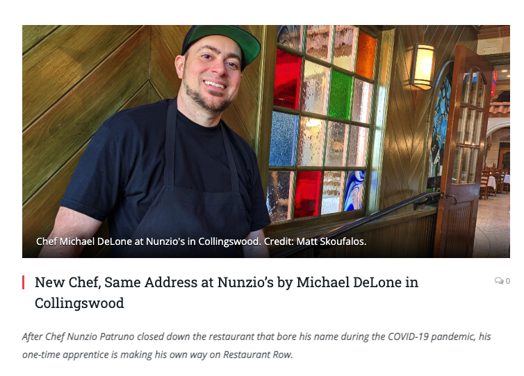 Chef Michael DeLone smiling in a restaurant with colorful stained glass windows behind him.