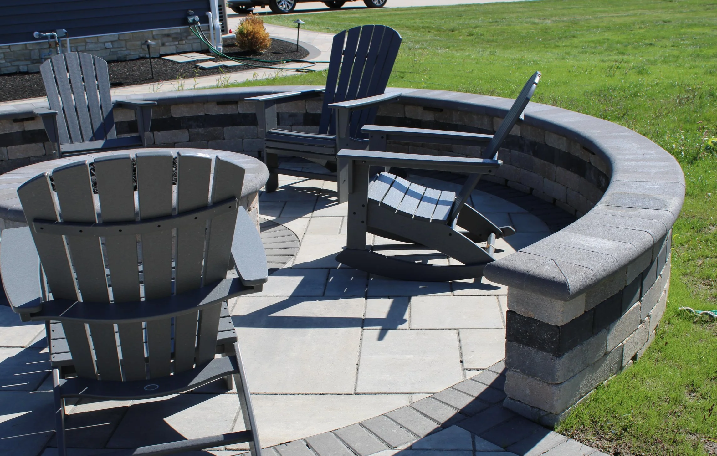 Curved seating wall around a paver patio with Adirondack chairs in Bay Village, OH