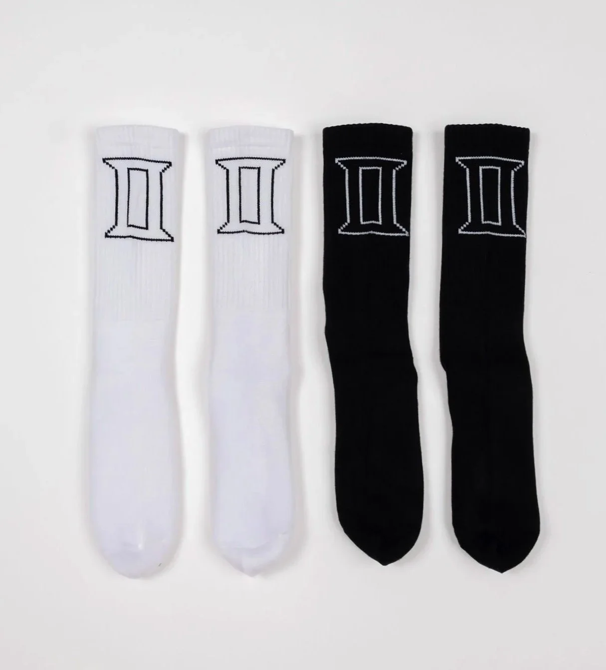 Two pairs of crew socks, one black pair and one white pair, each with contrasting outlined ‘II” logo near top