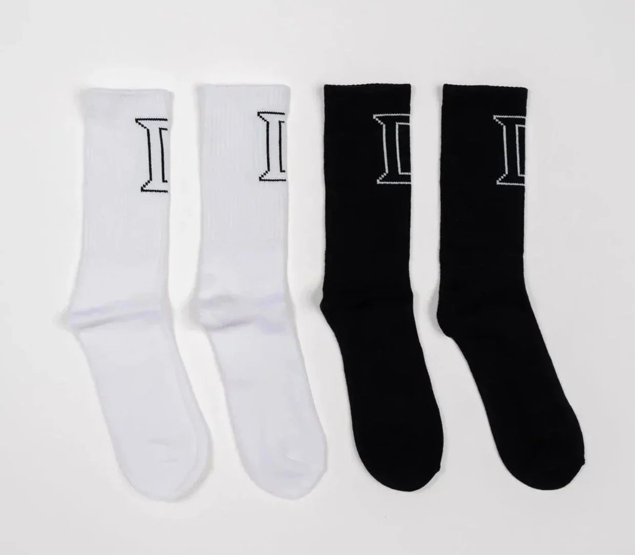 Side view of two pairs of crew socks, one black pair and one white pair, each with contrasting outlined ‘II” logo near top