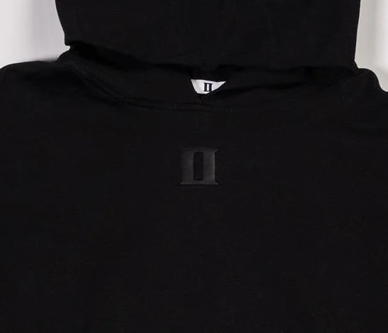 Close up of black pullover hoodie with small debossed ‘II’ logo below hood on front
