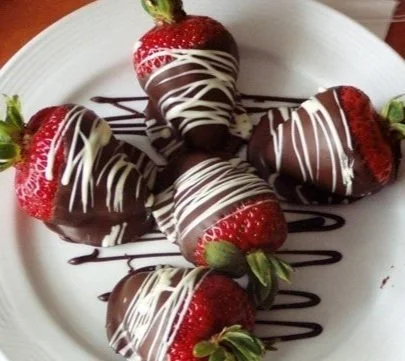 Strawberries dipped in chocolate with white chocolate drizzle on a plate.