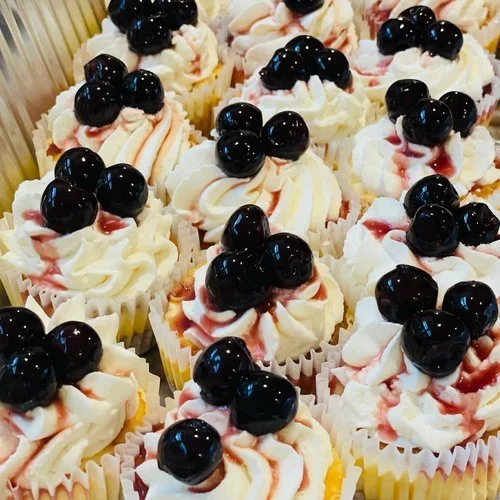 Cupcakes with whipped cream frosting and black cherries on top.