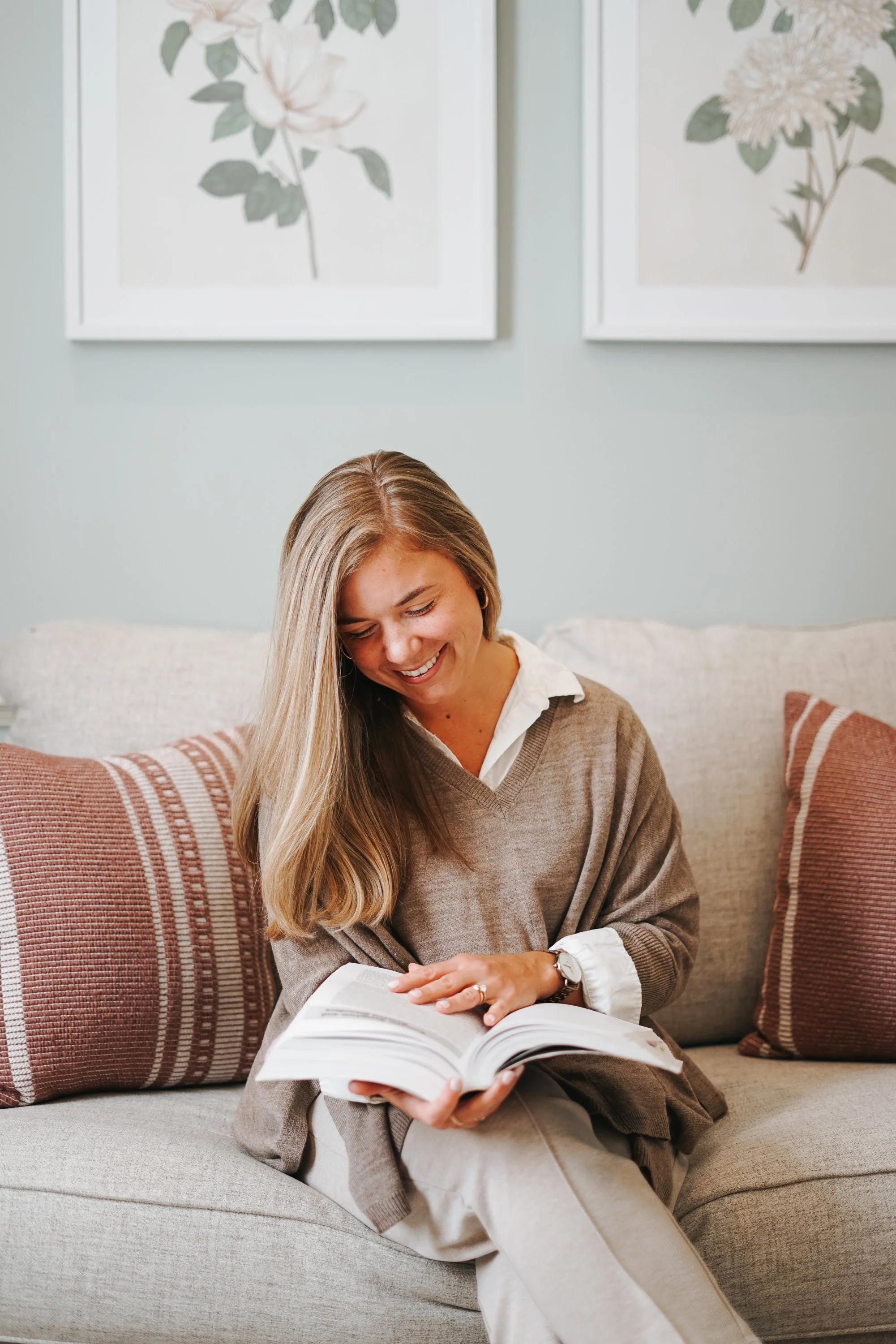 Young woman smiling and reading a book in a comfy therapy office.