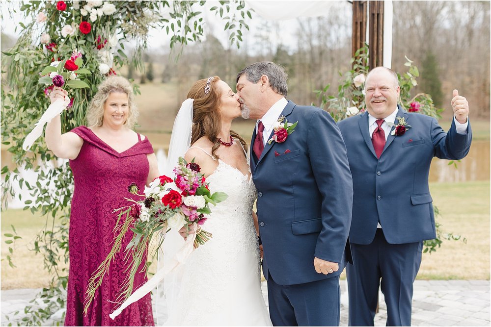 Photo of Bride and Groom Kissing with Bridal Party Cheering