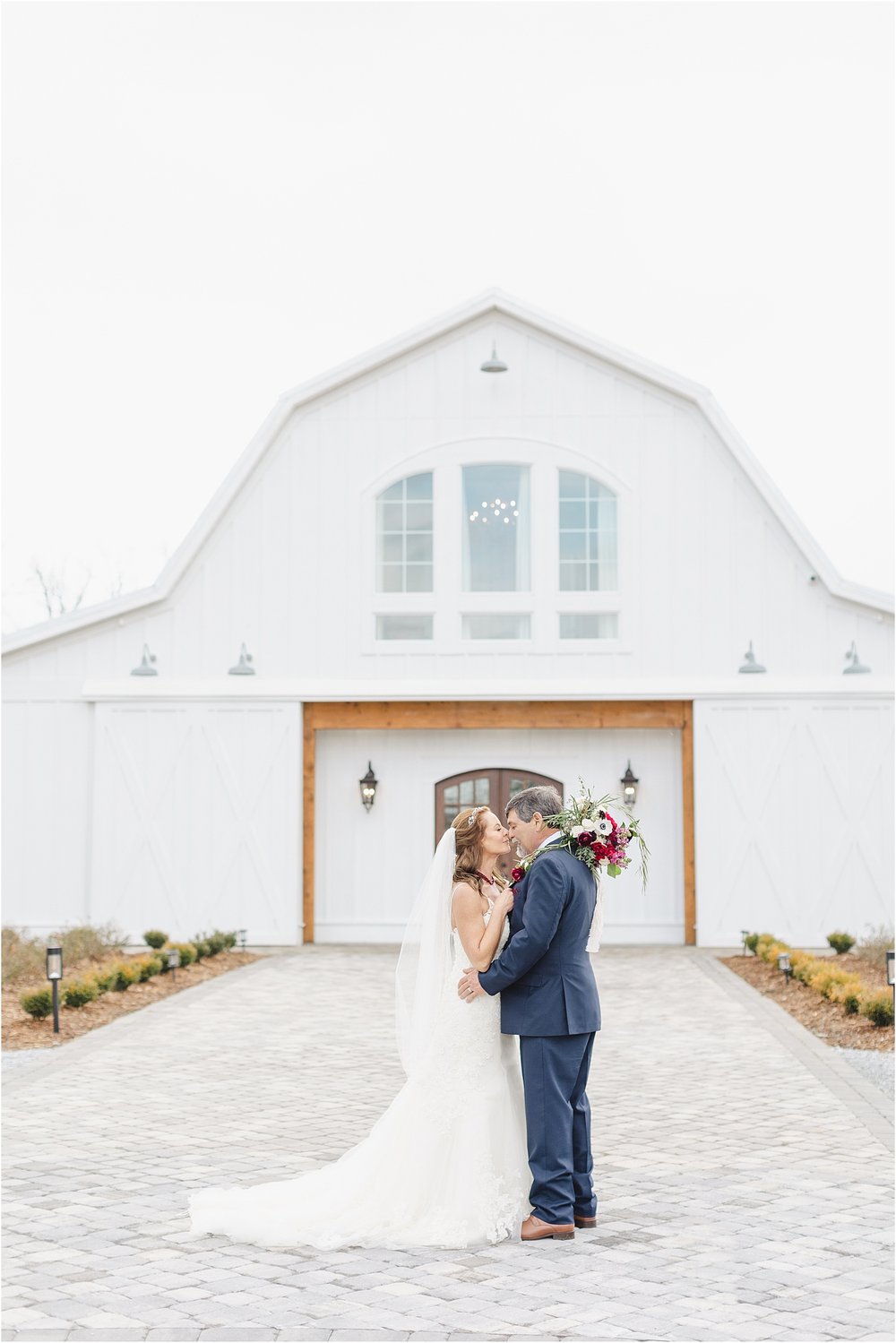 Posed Photo of Bride and Groom in Front of Barn Venue