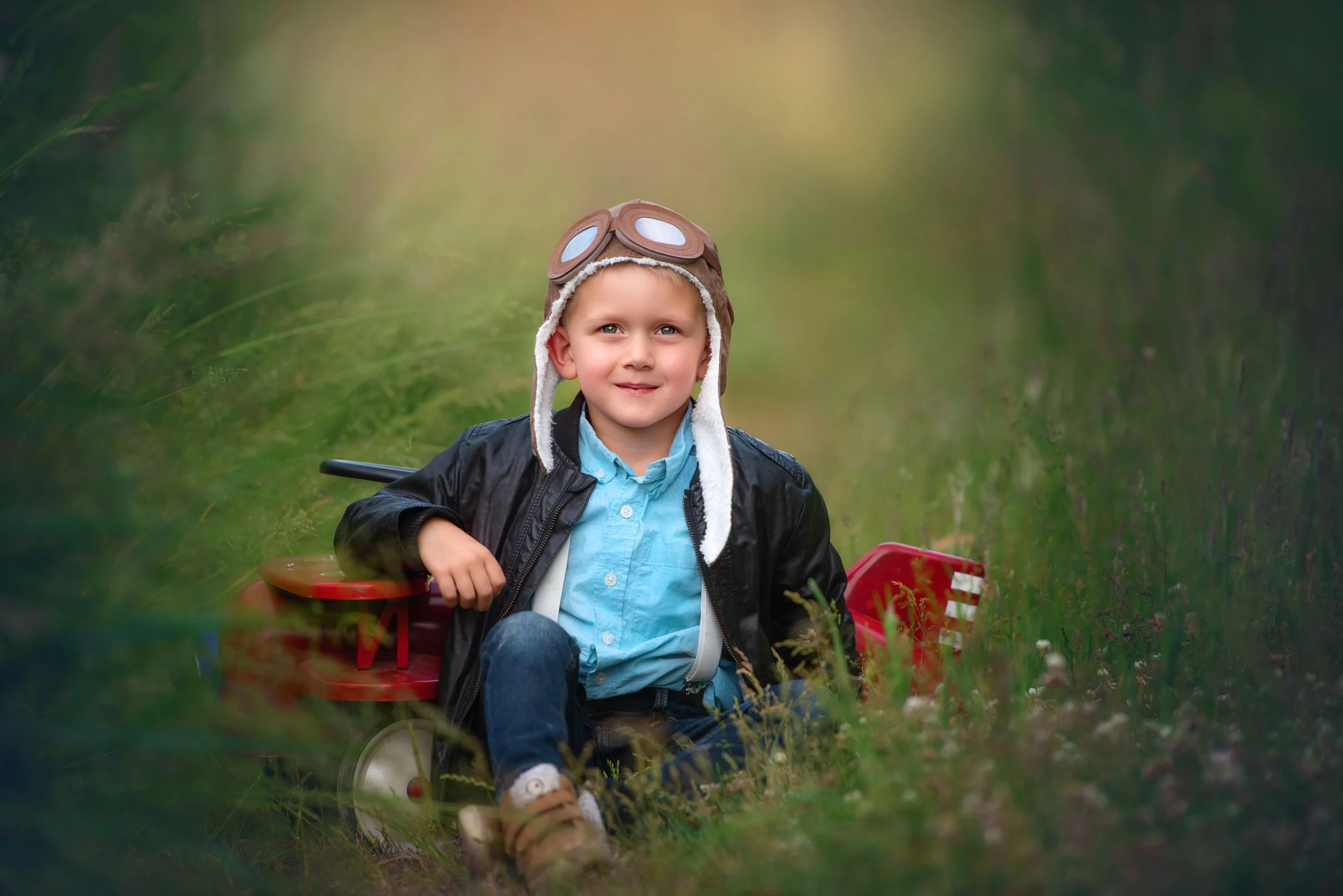 calgary children photographer boy sitting near red airplane.jpg