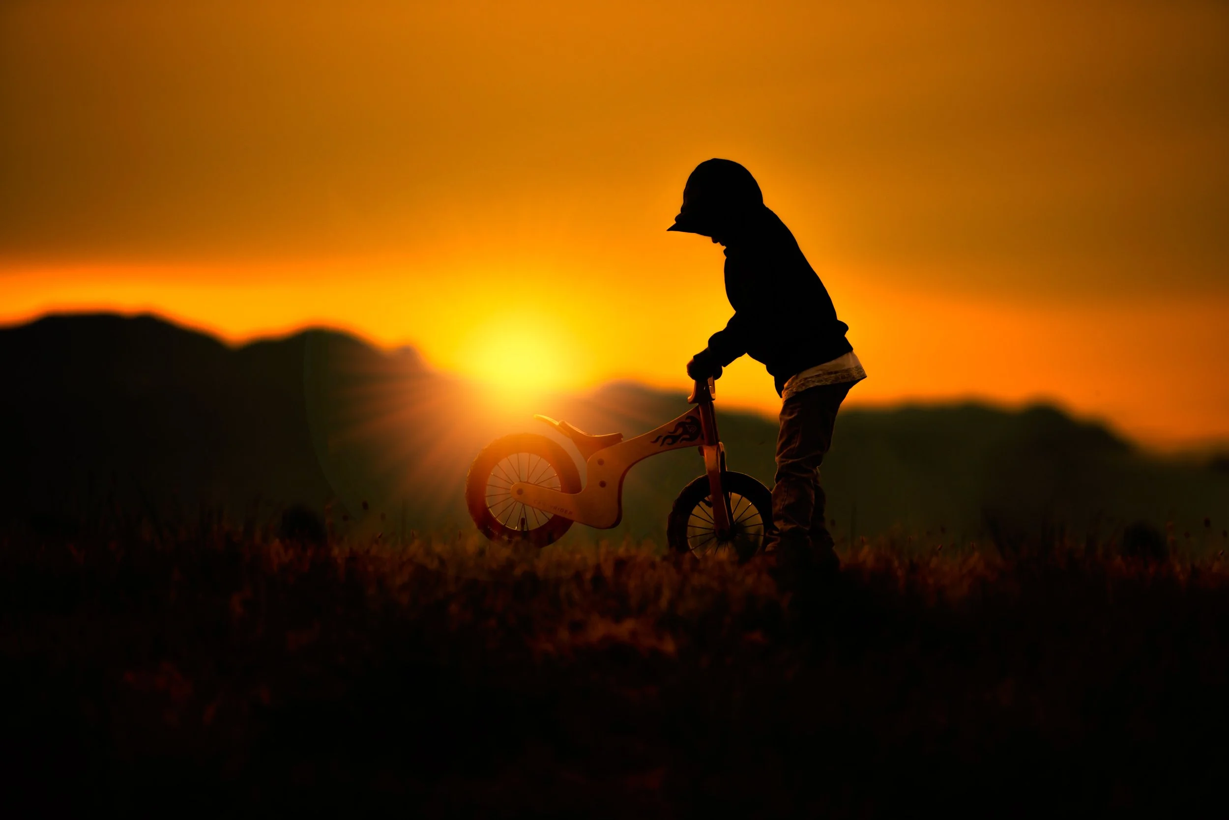 calgary children photographer boyplaying with his bike at sunset.jpg