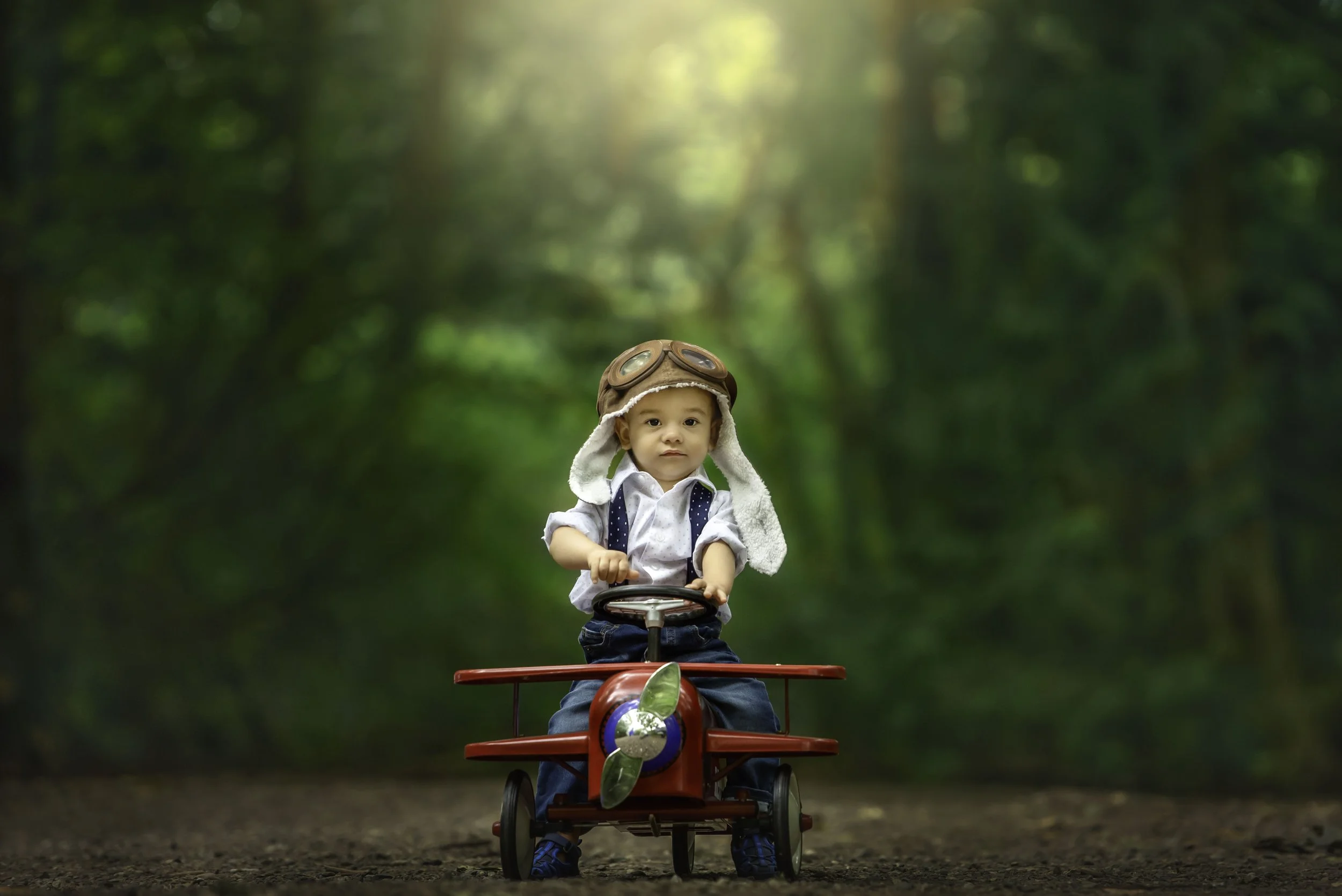 calgary children photographer boy sitting on red airplane.jpg