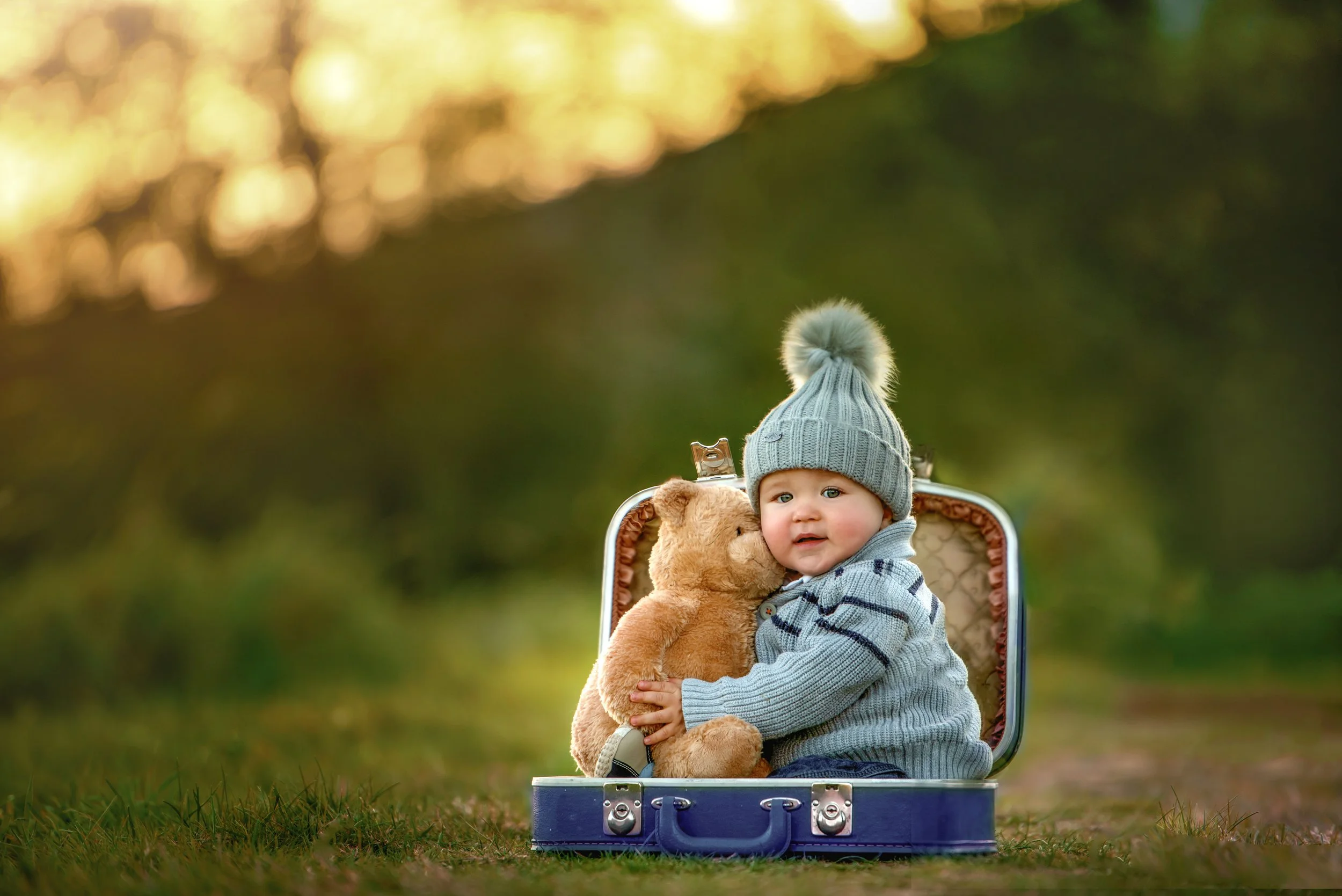 calgary children photographer boy sitting on suitcase outside.jpg