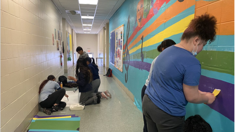 Step 4: Once students finished painting the sheets, they used a special glue to paste them directly to the wall. Once glued to the wall, the sheets become a permanent mural. 