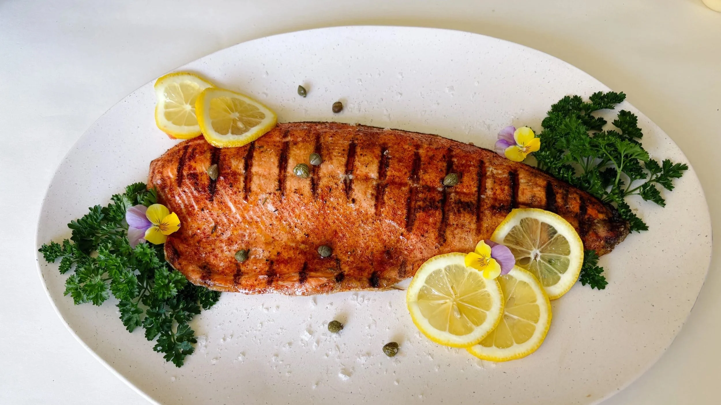 Grilling wild sockeye salmon on barbecue with lemon and herbs