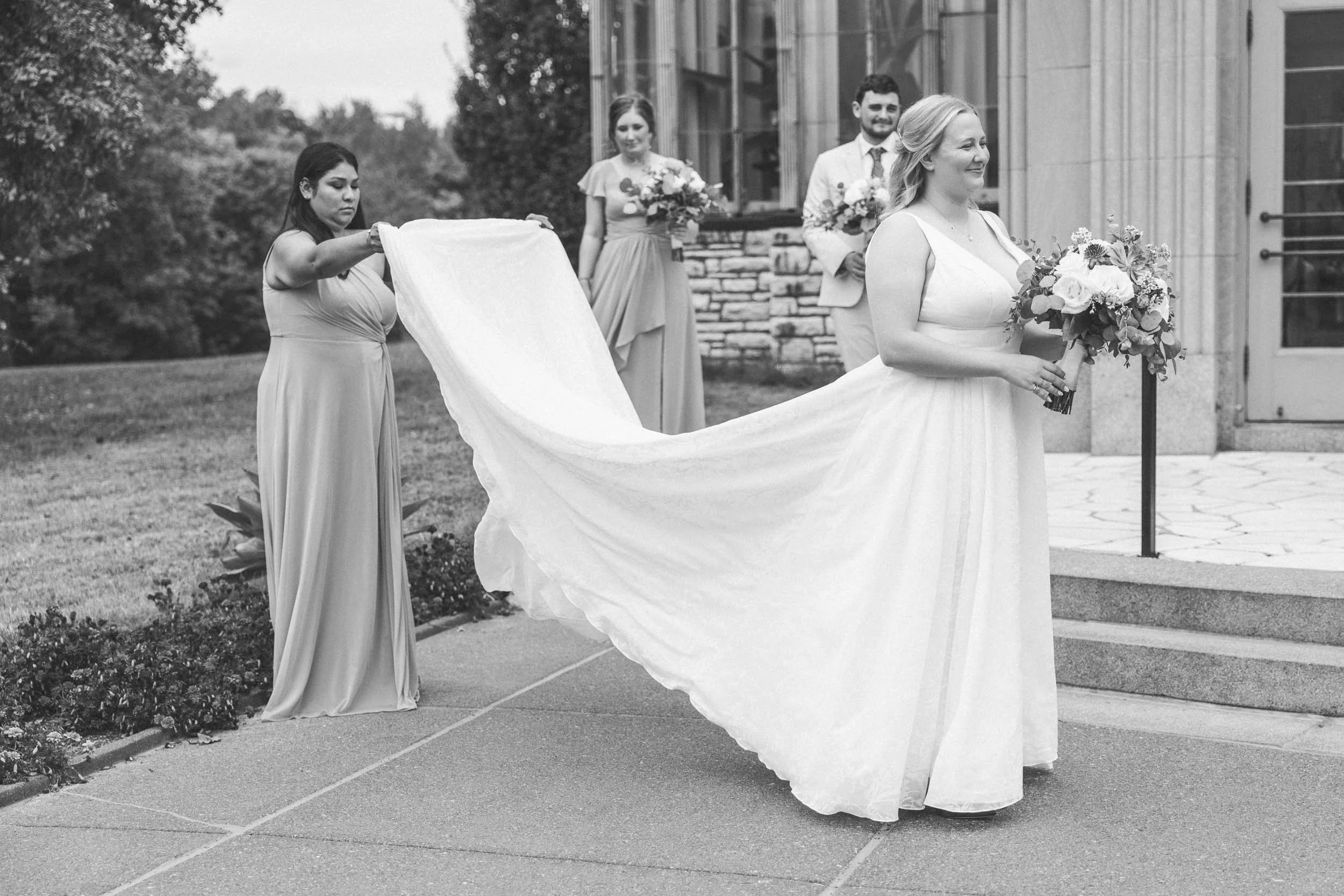 maid of honor helping the bride with her wedding dress for the first look