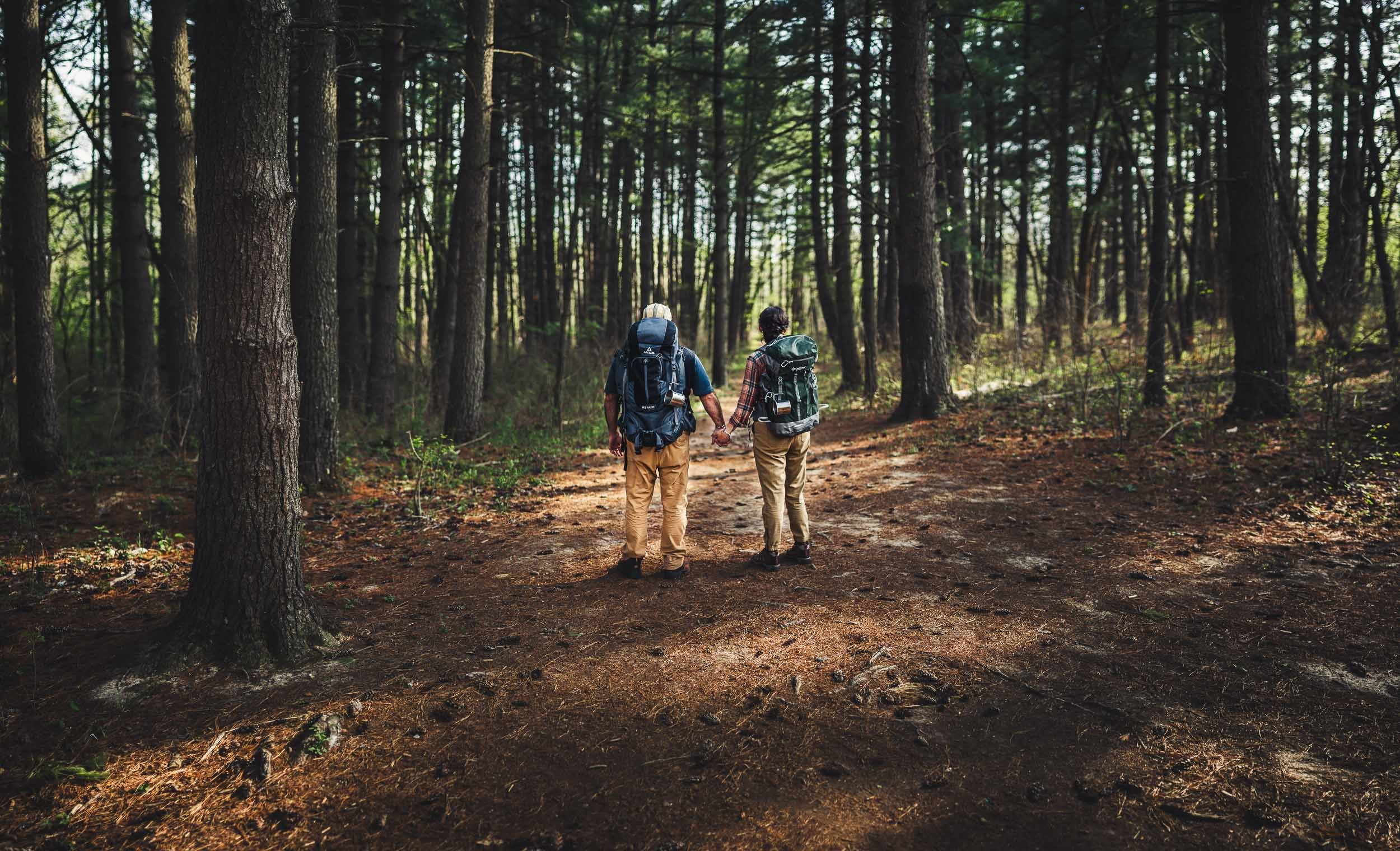 engaged couple holding hands wearing backpacks_busch wildlife