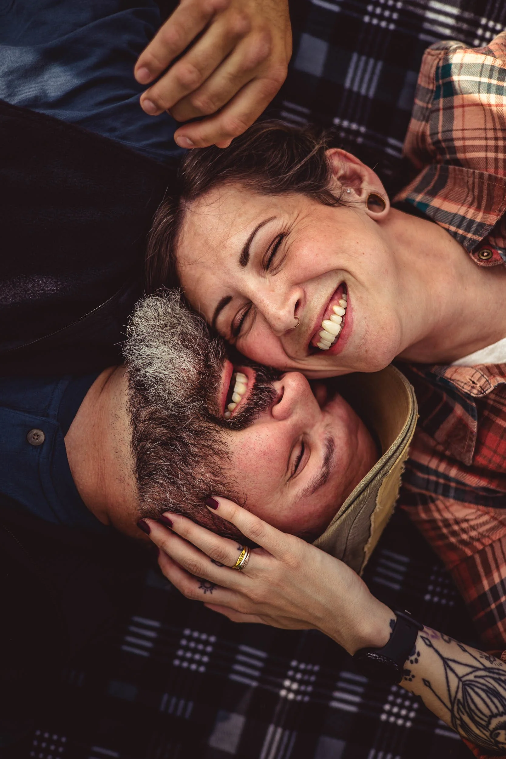 man and woman cuddling and laughing on a camping blanket_busch wildlife engagement session