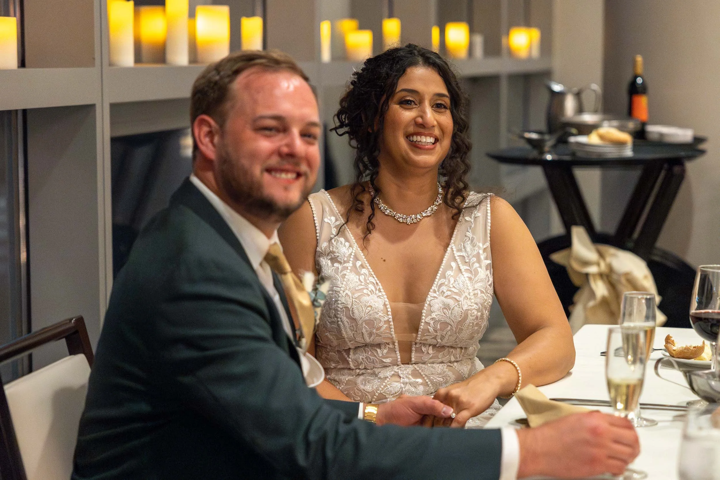 bride laughing during wedding reception as her father is giving a speech