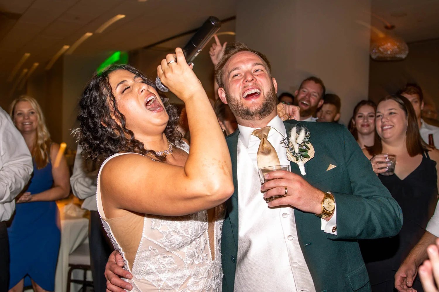 bride and groom singing on the wedding reception dance floor surrounded by wedding guests