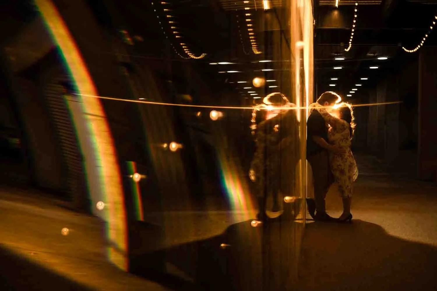 couple standing agaist a wall kissing with stringed lights-city foundry engagement photos