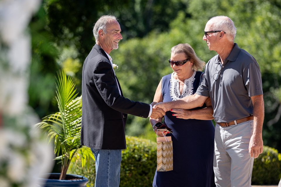 wedding guests shake grooms hand entering ceremony-st louis wedding photography