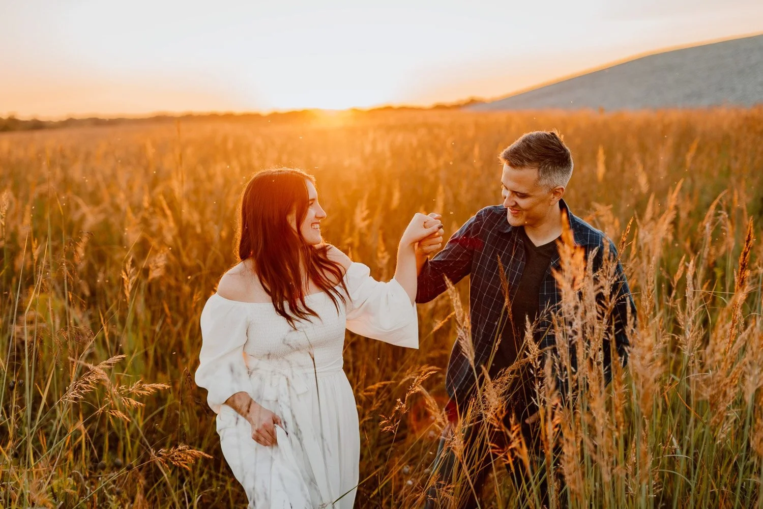 couple walking through a wheat field during golden hour