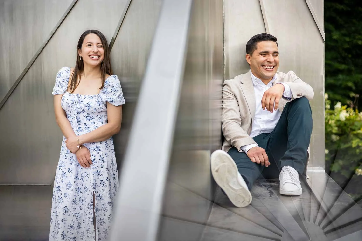 engaged couple laughing and standing against a work of art in forest park-engagement photography