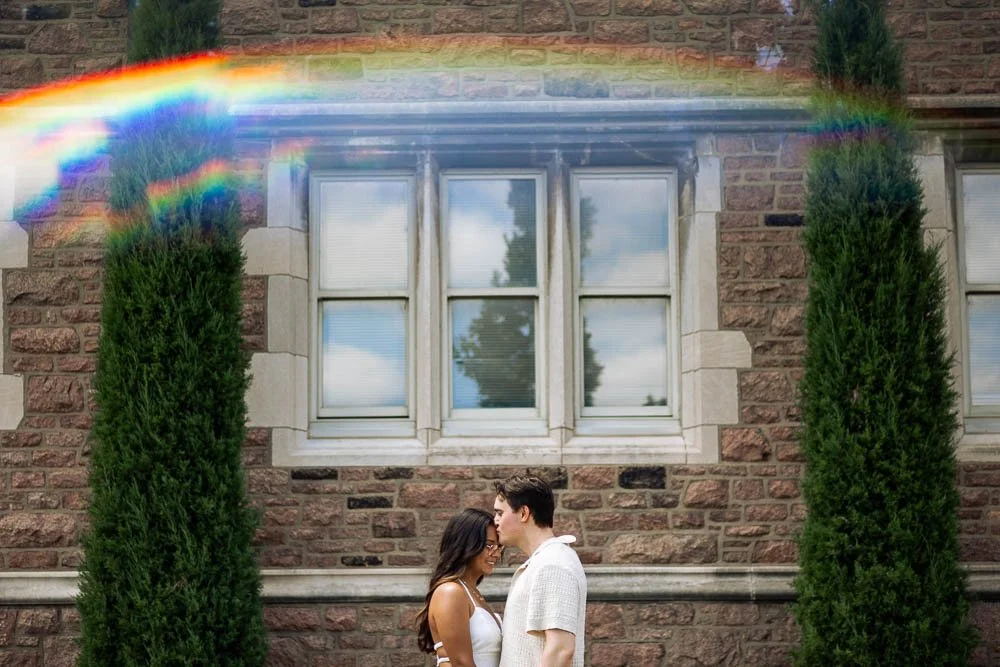 couple kissing between two trees with rainbow-saint louis washington university engagement photo