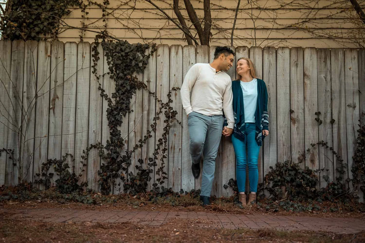couple leaning against a fence with brick sidewalk-engagement photography soulard saint louis mo