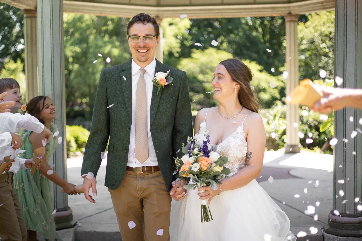 bride and groom walking back down the wedding aisle while wedding guests throw flowers