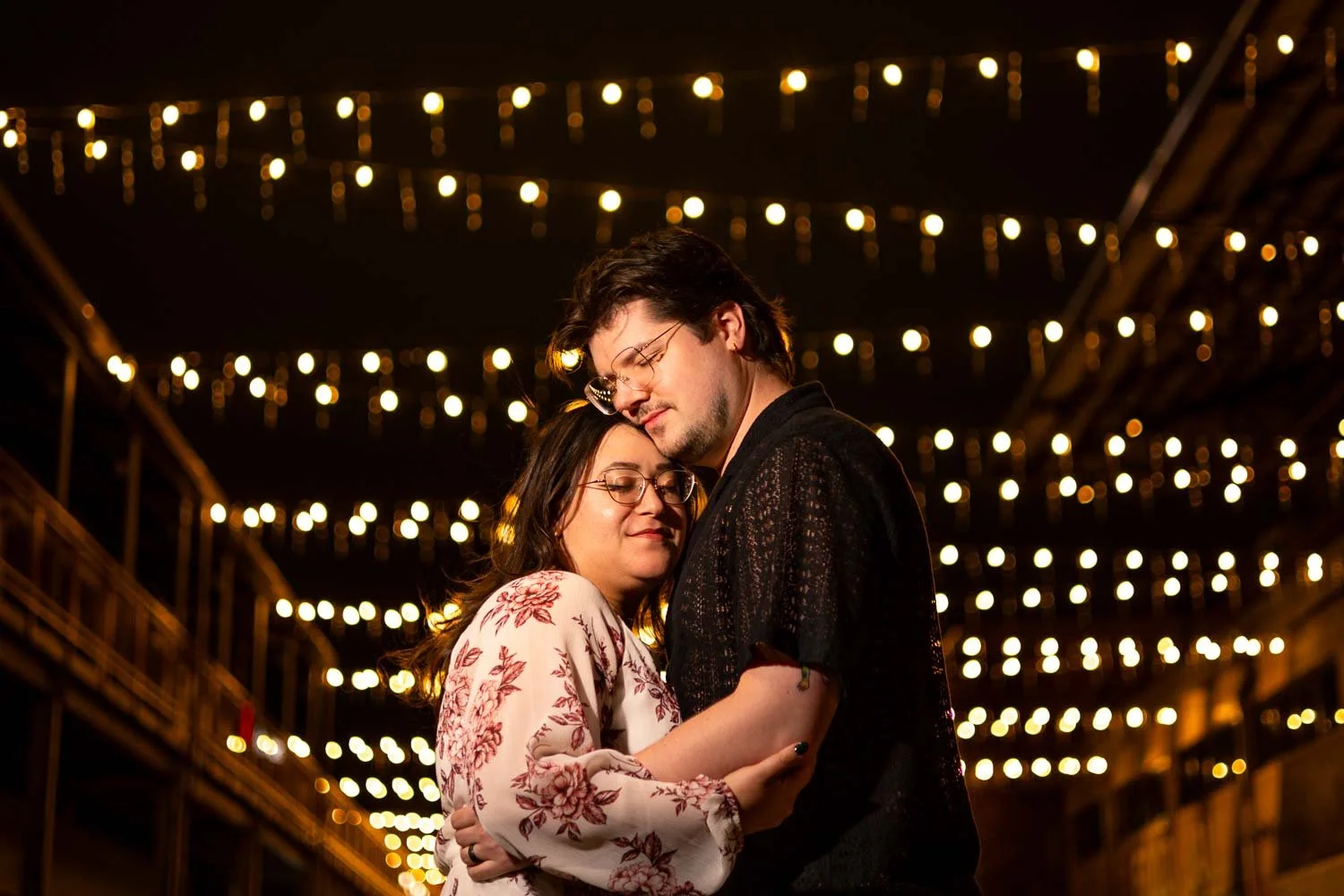 couple snuggling under string lights at night-city foundry saint louis mo