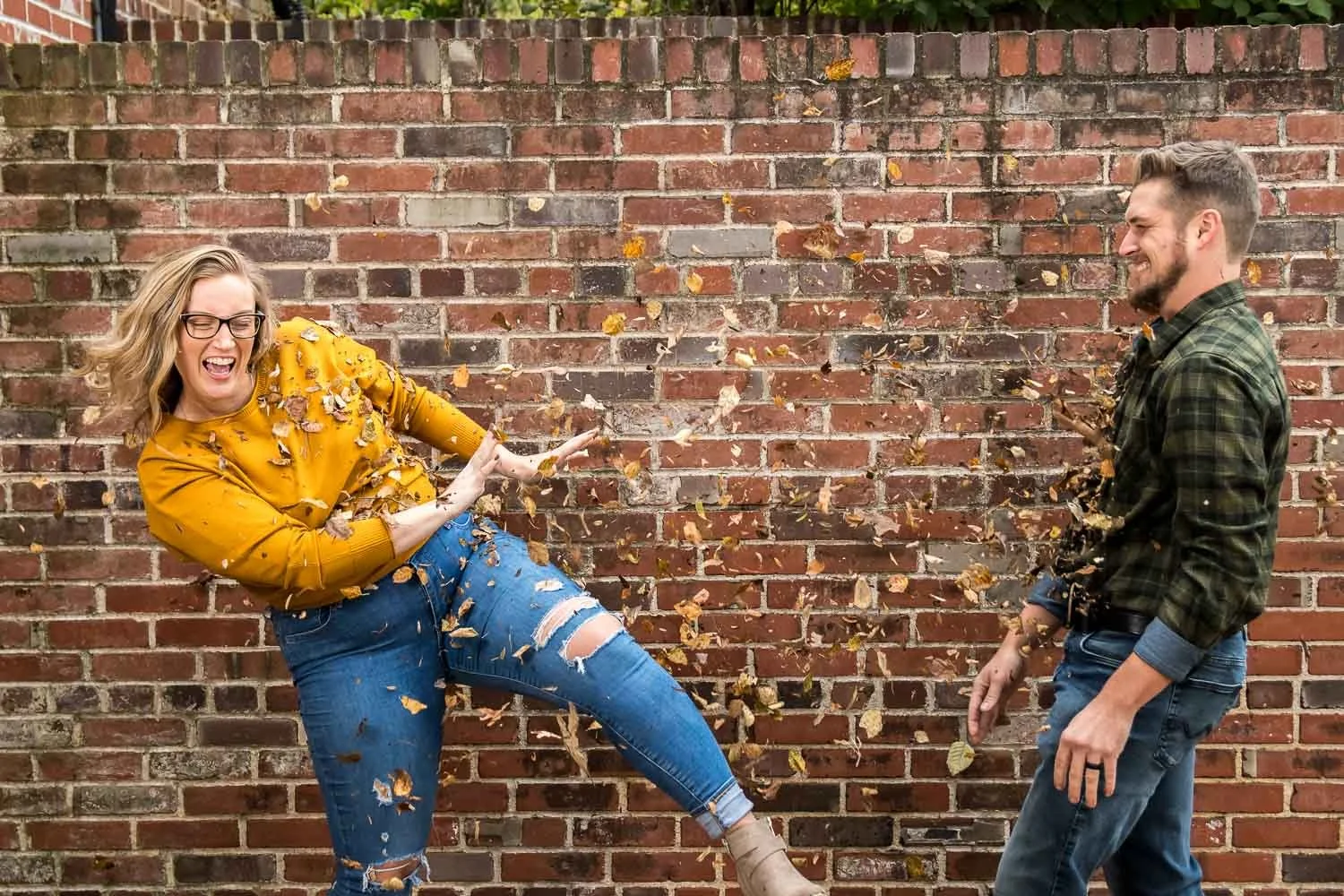 man and woman throwing leaves at each other-saint louis engagement photography