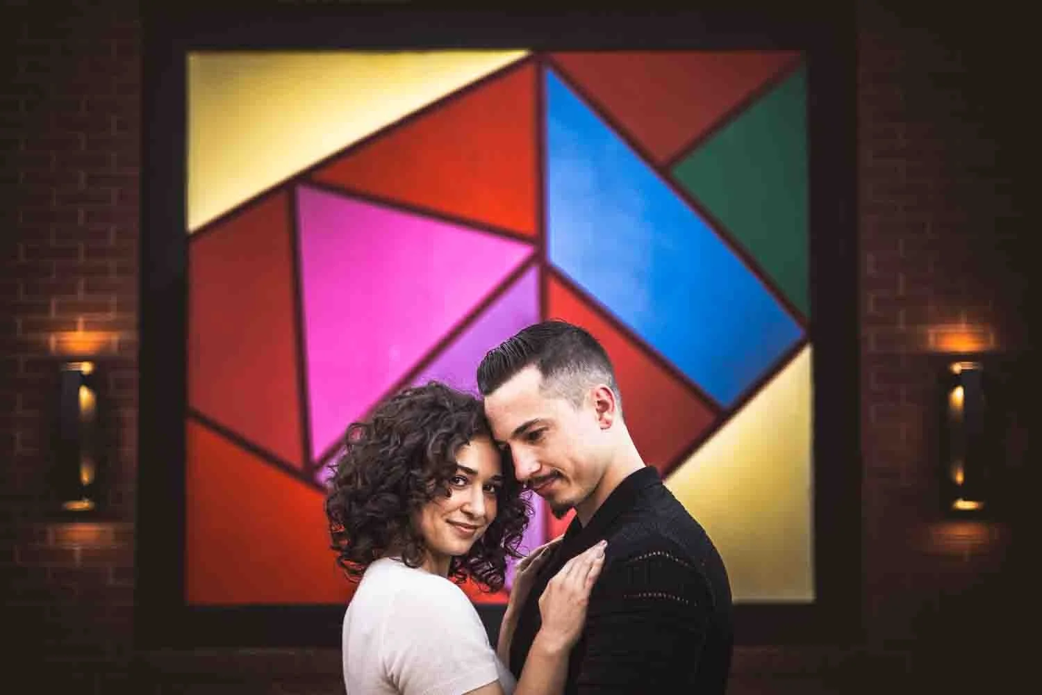 couple snuggling in front of mural art piece-university city engagement photos