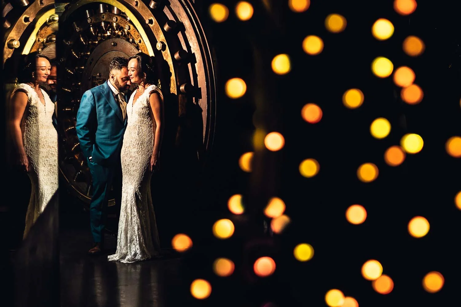 Bride and groom wedding portrait by bank vault door with stringed lights-wedding photographer st louis