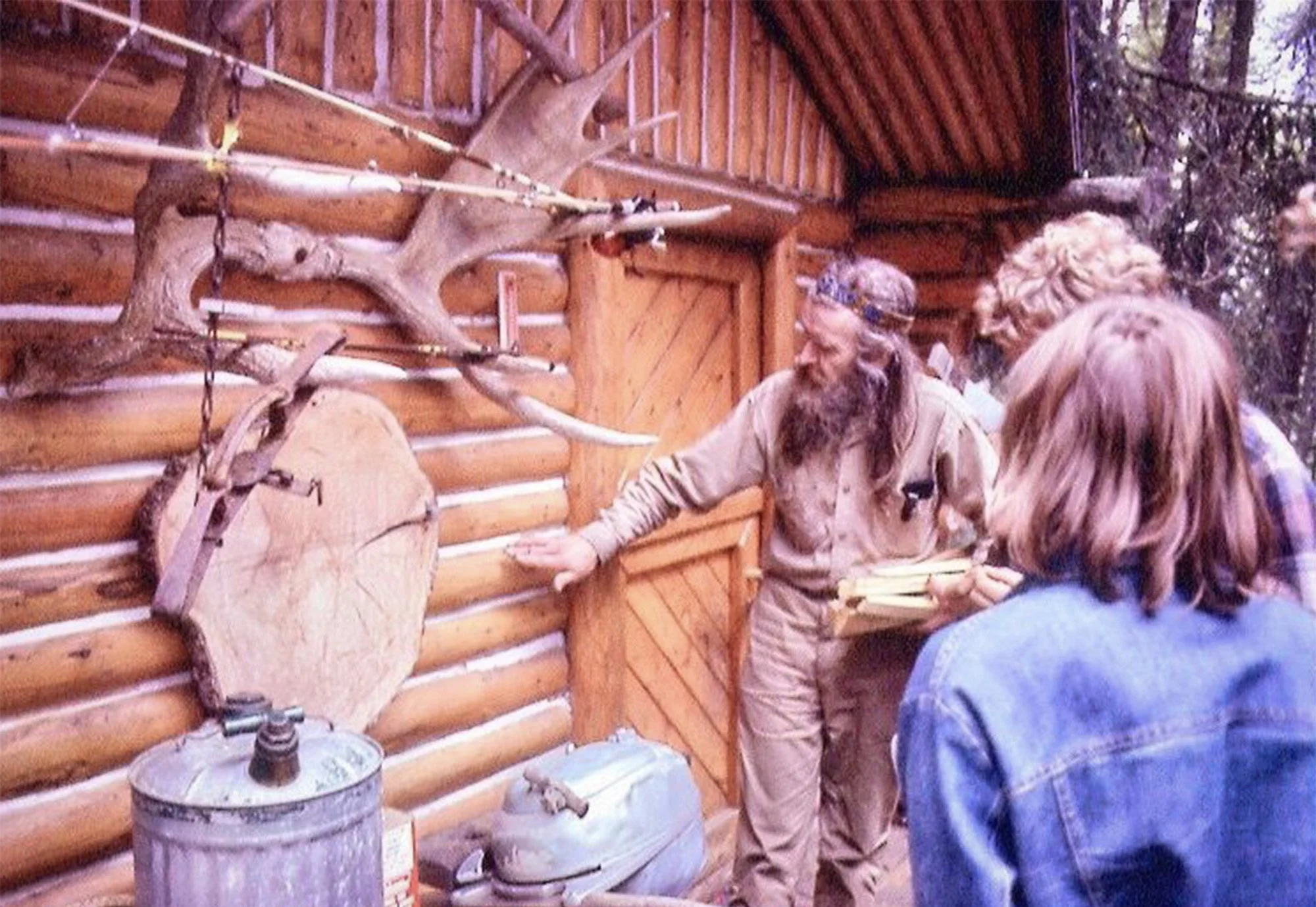 log cabin with moose antlers, Wendell showing cabin to young people