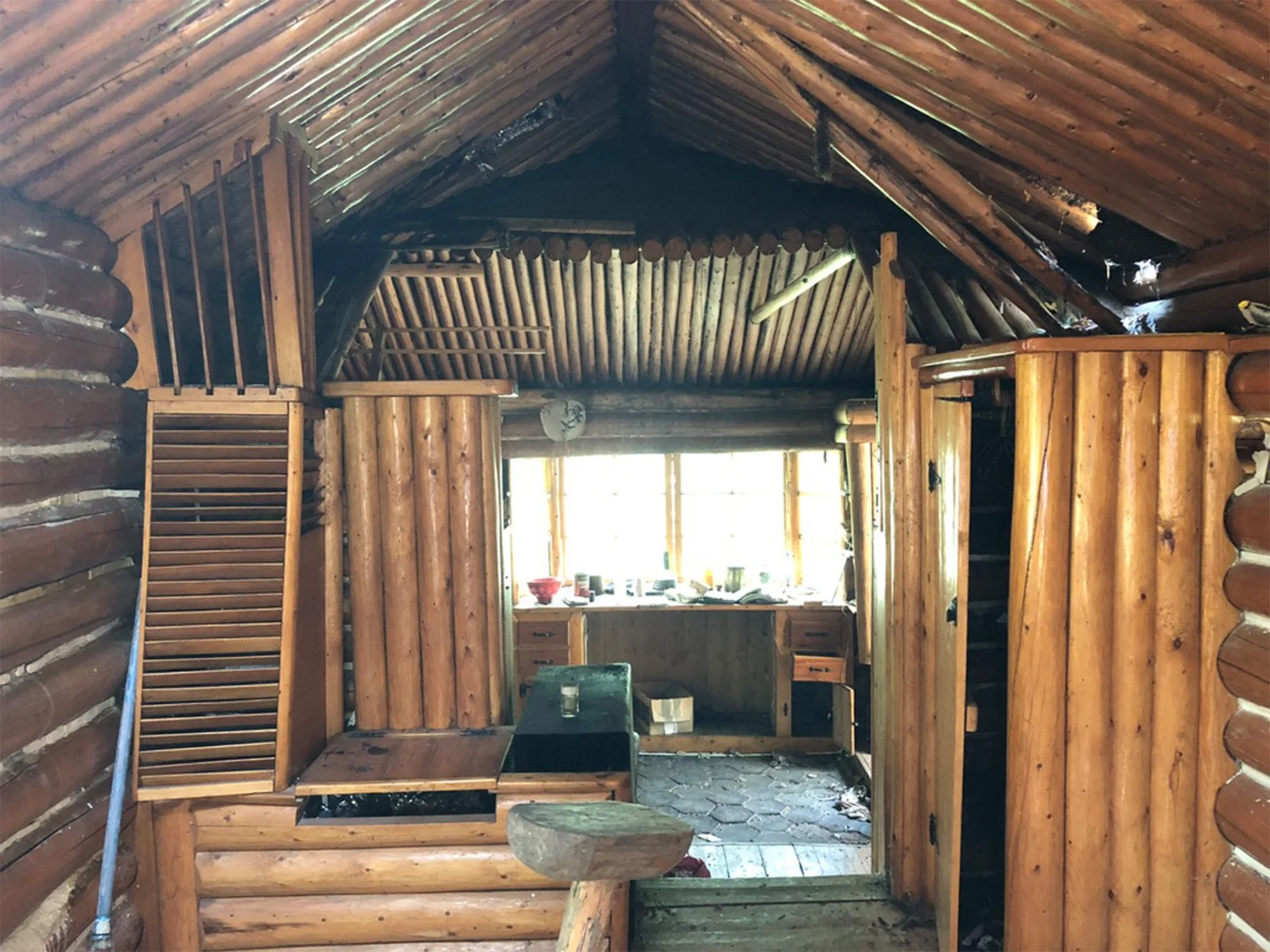 The inside of a vintage log cabin with a built-in desk and loft