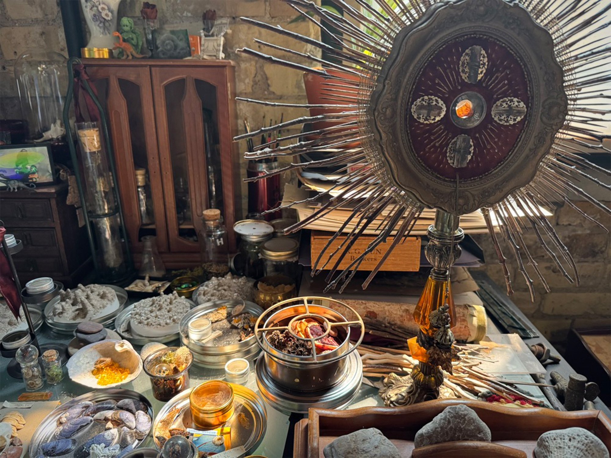 desk cluttered with natural objects and sculptures, orange light coming from window