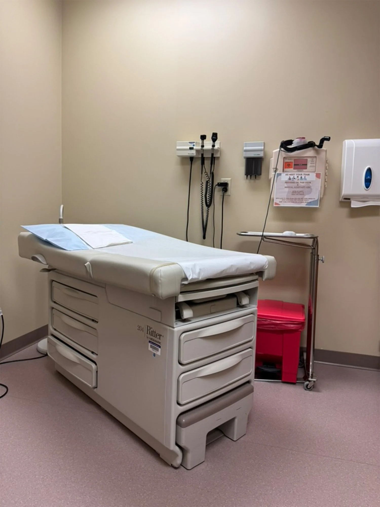 a medical exam room interior with an exam table covered in paper and gown