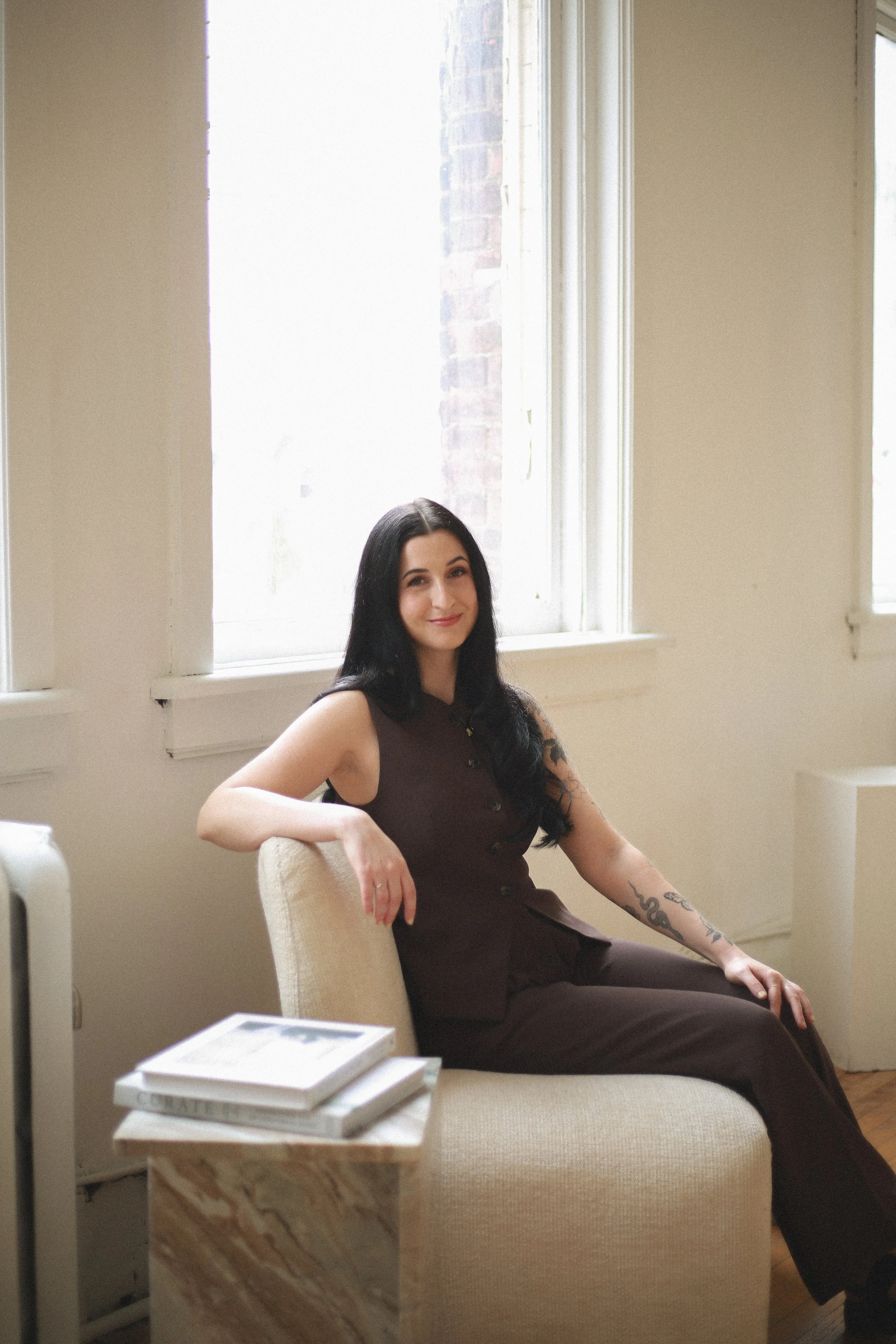 Female entrepreneur sitting in chair smiling at camera during brand shoot.