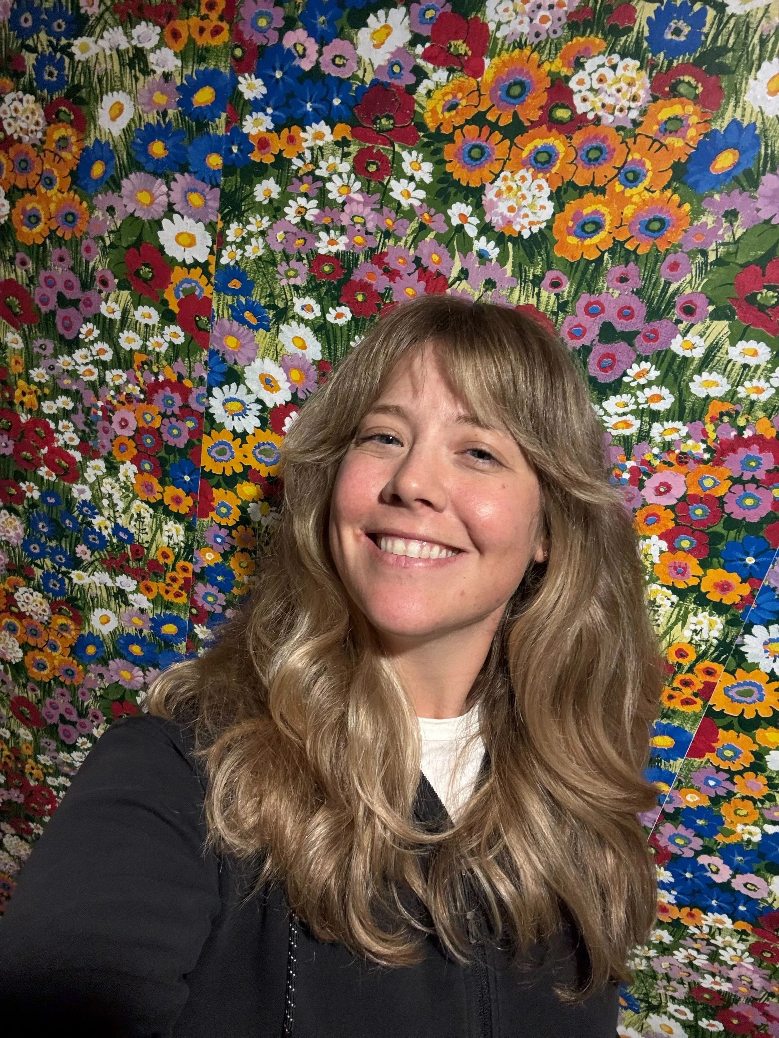Woman smiling with flower wallpaper behind