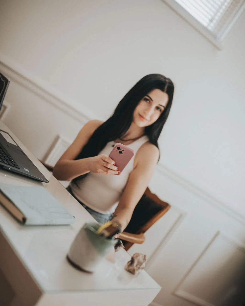 Woman with dark hair and phone at a desk