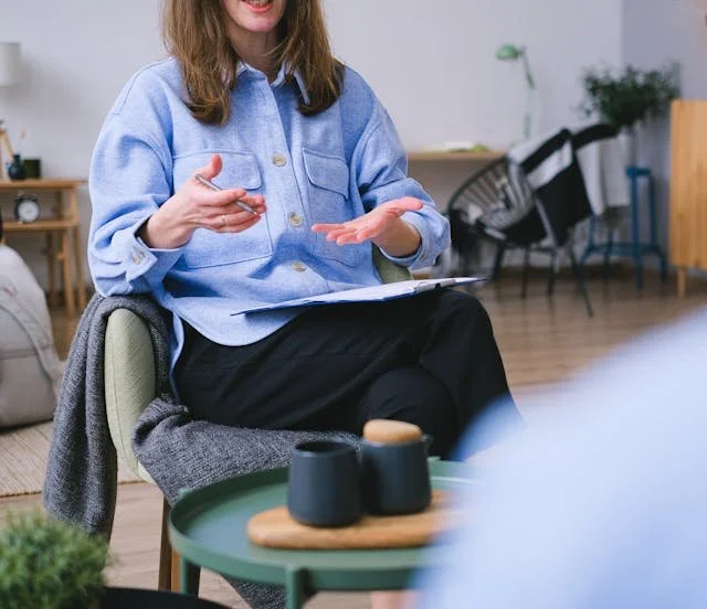 The image of LGBTQ BIPOC transgender counsellor in Burnaby sitting with someone, looking pensive to accompany a blog post about whether am I trans enough. The article is written by an LGBTQ therapist Burnaby running a counselling in Burnaby