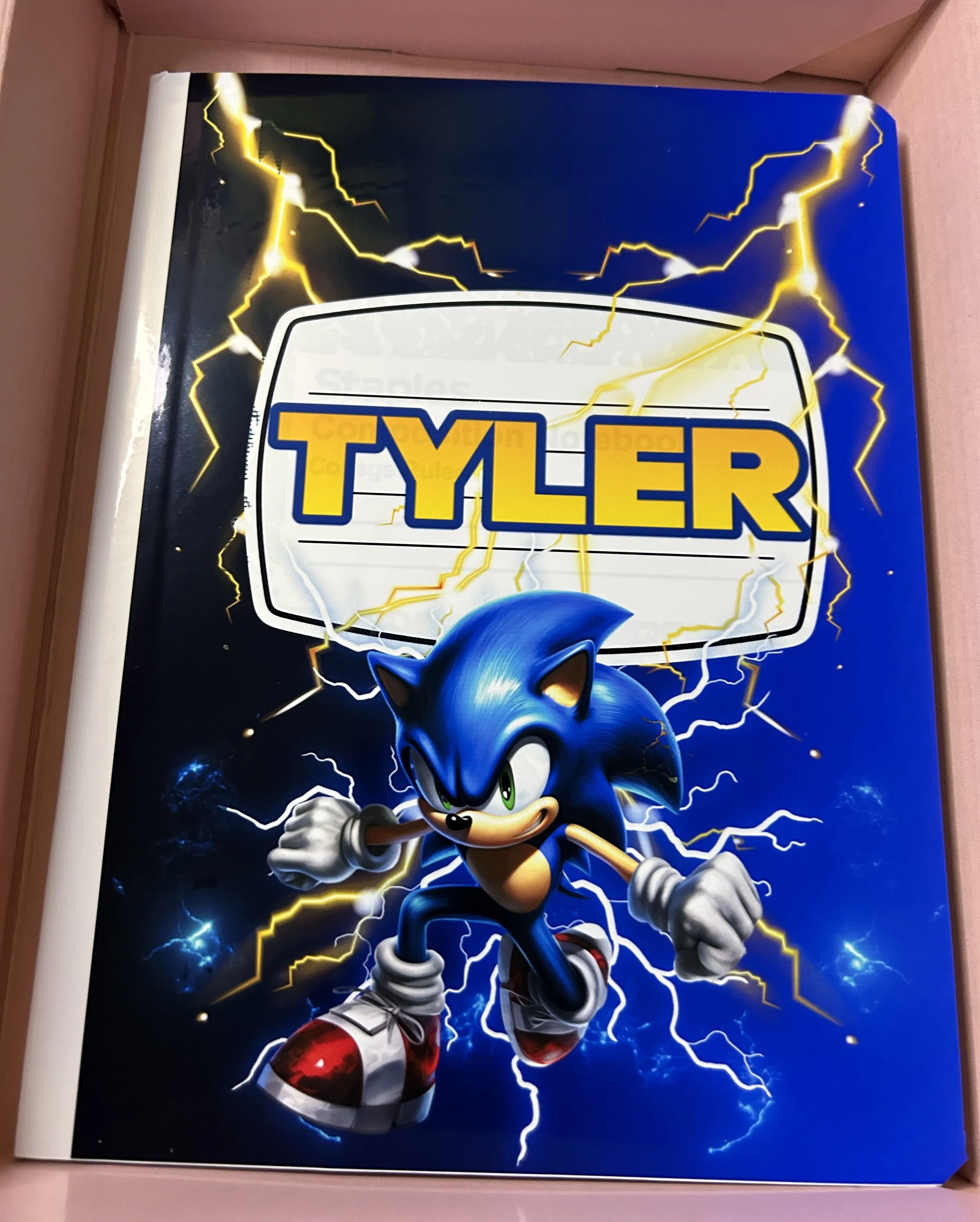 Notebook cover featuring a blue animated hedgehog character surrounded by electric sparks, with the name "Tyler" prominently displayed.